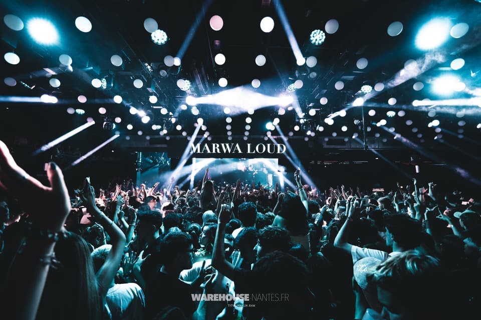 Concert de Marwa Loud au Warehouse Nantes : croisillons de beams blancs sous le plafond de sphères, foule bras levés