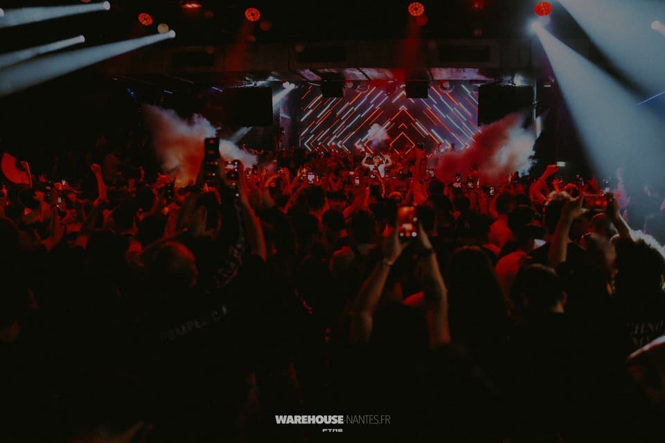 NRT avec Nico Moreno au Warehouse Nantes : wash rouge sur la foule téléphones levés, mur LED à chevrons, fumée
